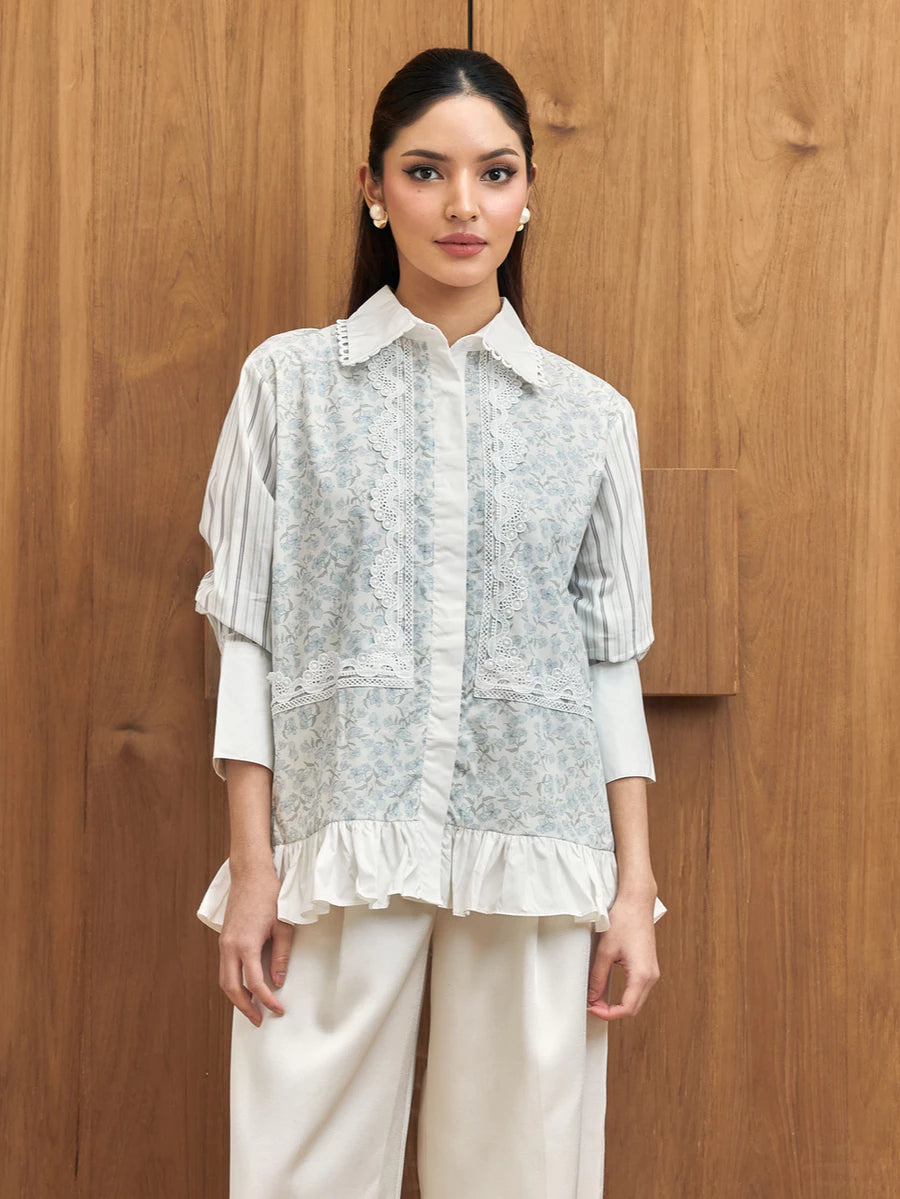 Woman wearing a light-colored blouse with ruffled details by Studio Tui against a wooden background