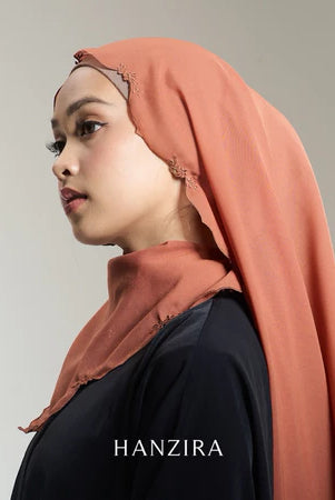 A woman wearing an orange pashmina scarf with embroidery, branded by HANZIRA.