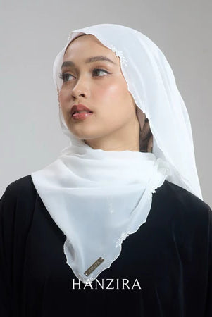 A woman wearing a white pashmina with embroidery, branded by HANZIRA.