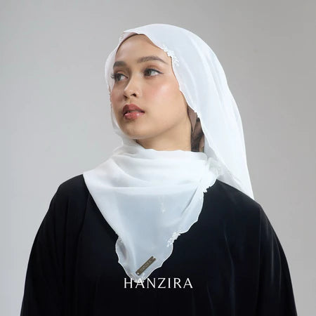 A woman wearing a white pashmina with embroidery, branded by HANZIRA.