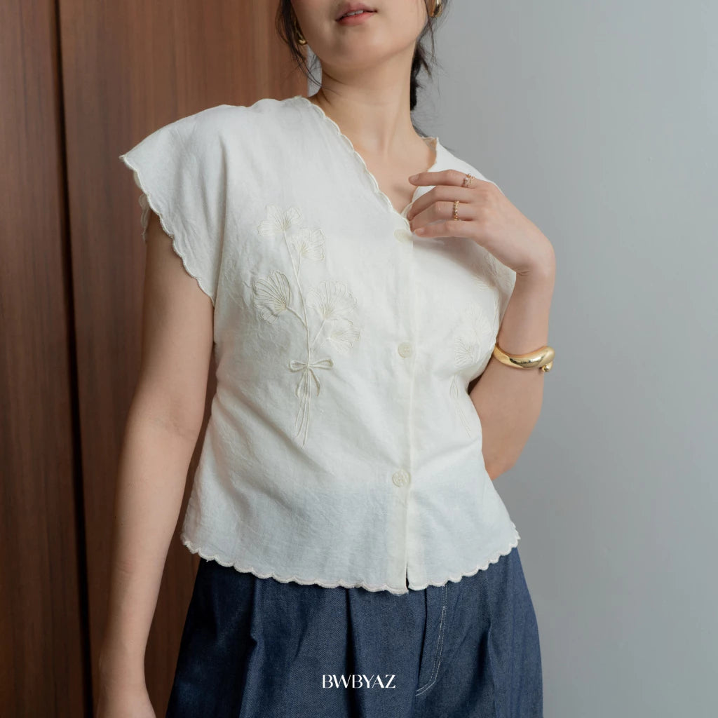 A person wearing a white Alaia embroidery tie vest with short sleeves and a v-neck neckline from BWBYAZ.