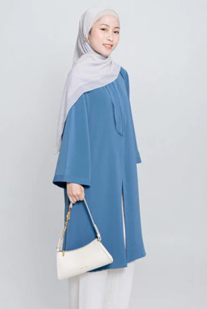 Seorang wanita menggunakan Aletha Tunic berwarna denim, sebuah tunik yang terbuat dari Cotton Bordir premium yang memberikan kenyamanan maksimal, dari Vlowy.