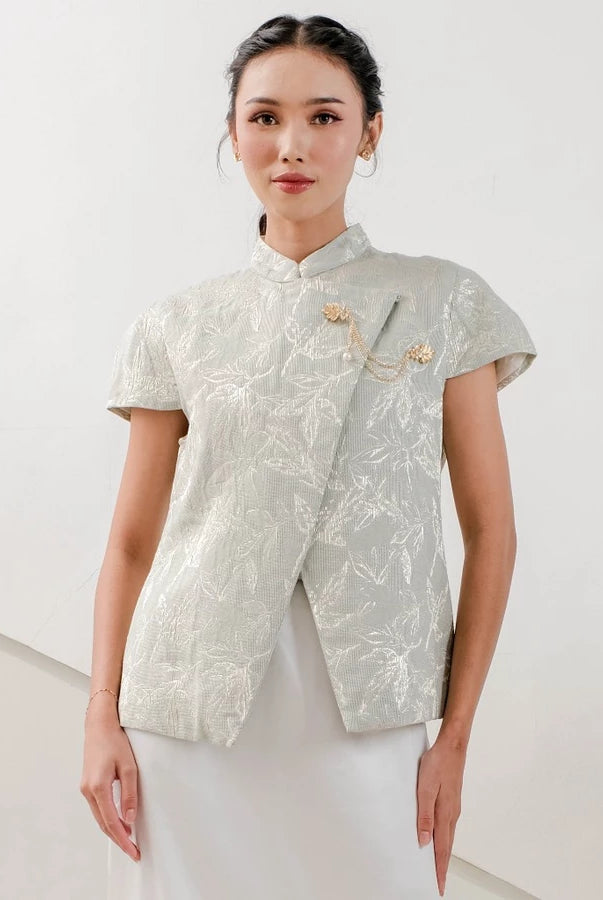 Woman wearing a sage-colored traditional outfit by Holy Peony with floral patterns on a white background