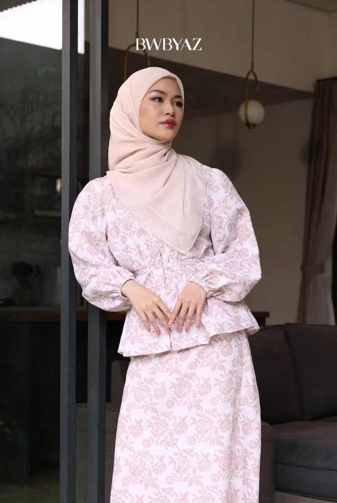 A person wearing a pink Alisha blouse with a floral pattern, featuring a loose fit and front waist tie from BWBYAZ.
