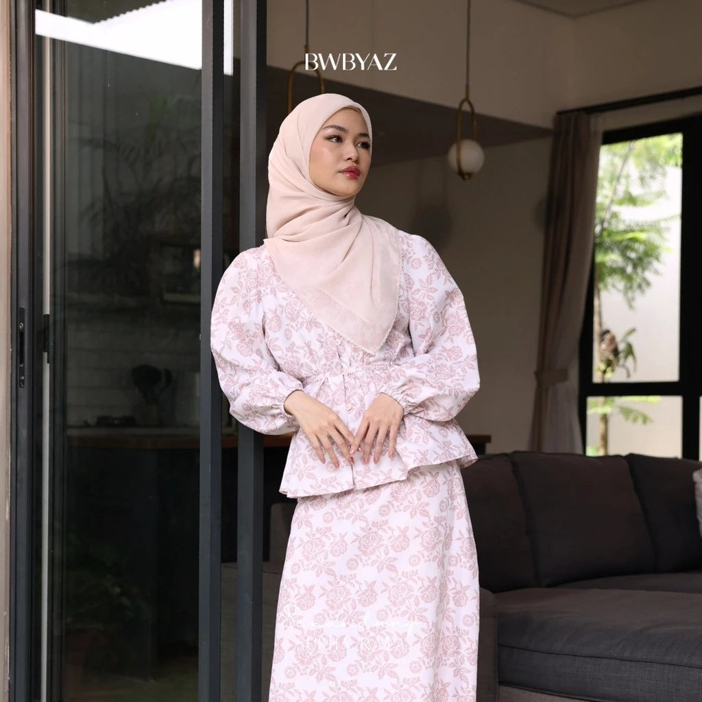 A person wearing a pink Alisha blouse with a floral pattern, featuring a loose fit and front waist tie from BWBYAZ.