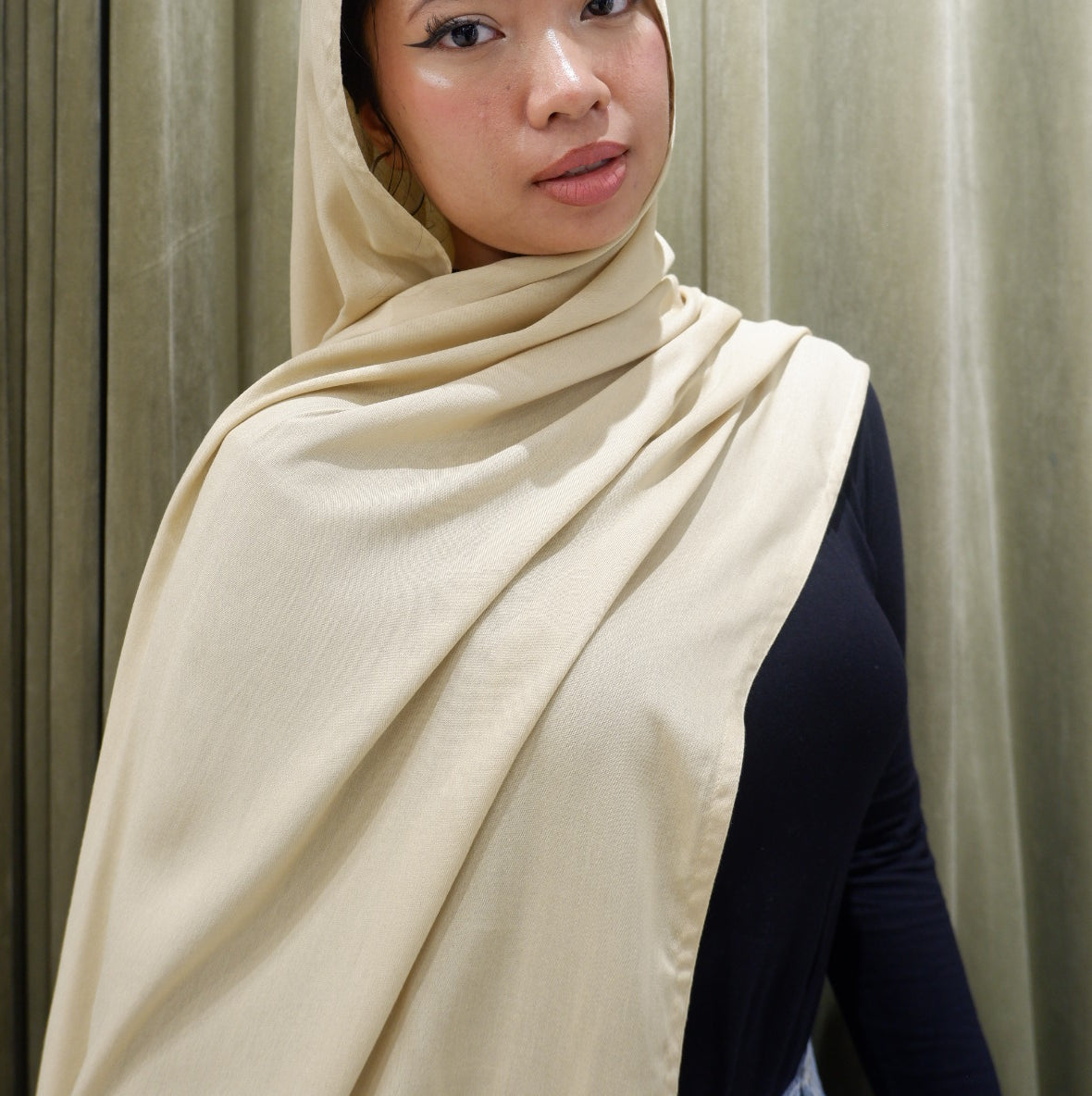 Woman wearing a buttercream hijab pashmina viscose against a wooden background