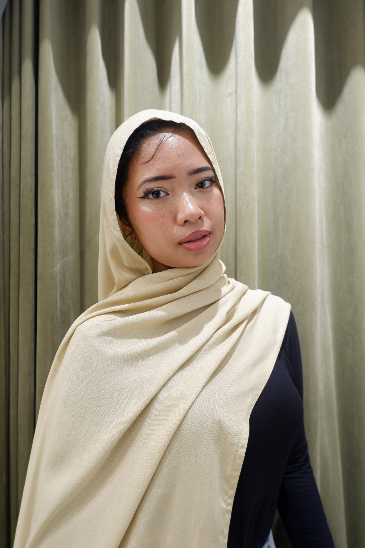 Woman wearing a buttercream hijab pashmina viscose against a wooden background