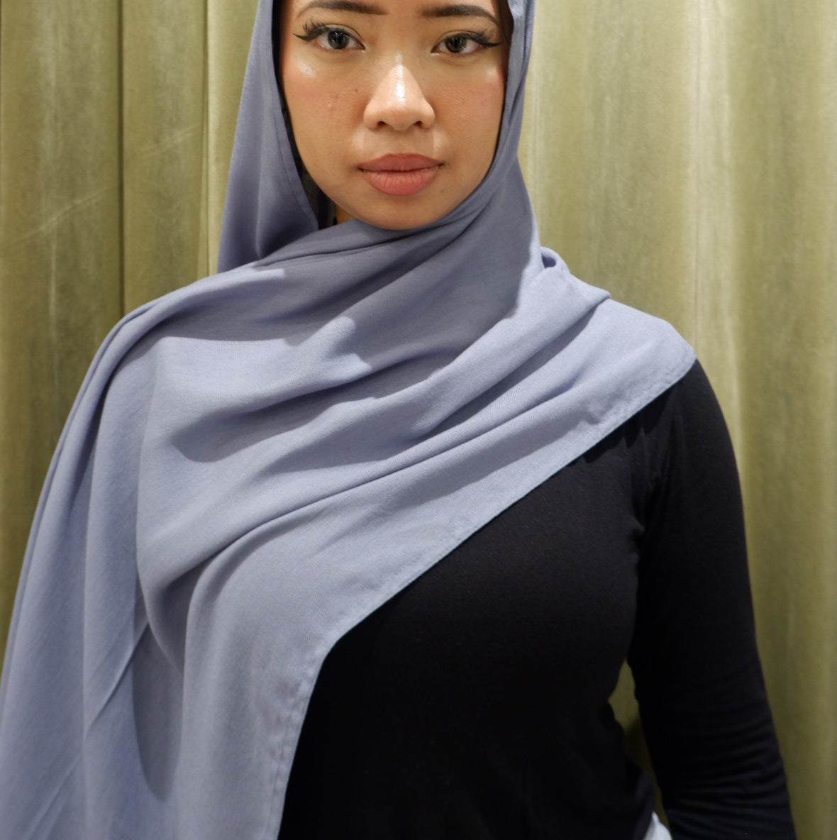Woman wearing a denim-colored hijab pashmina viscose against a wooden background