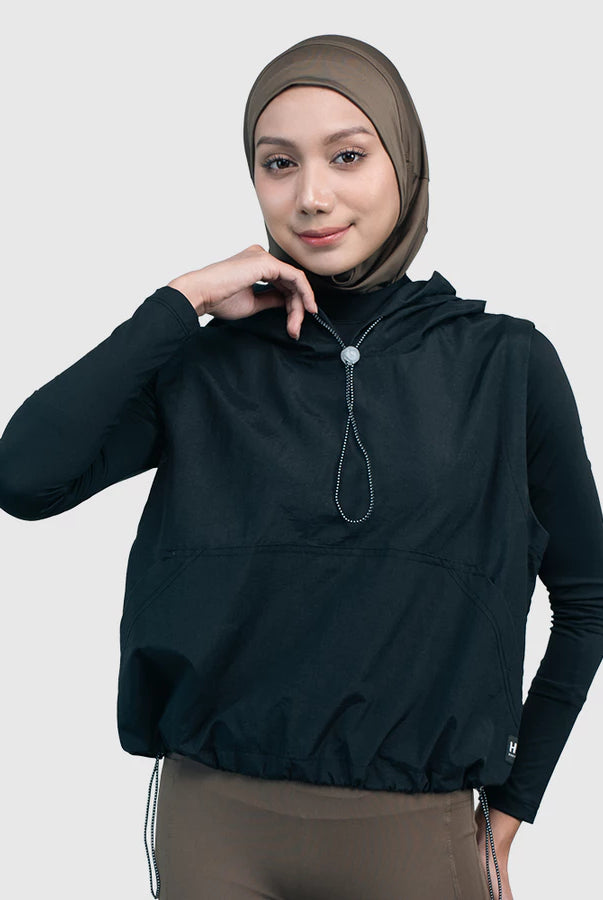 Woman wearing a black hooded vest by HIA with a white background