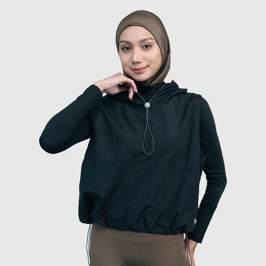 Woman wearing a black hooded vest by HIA with a white background