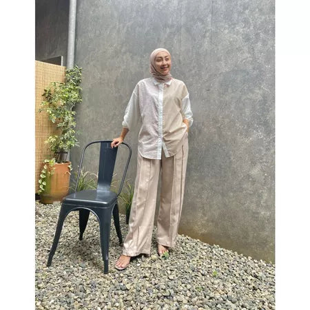 A person standing next to a metal chair wearing a beige shirt by Abame and matching pants with a round neckline, short sleeves, and a casual fit.