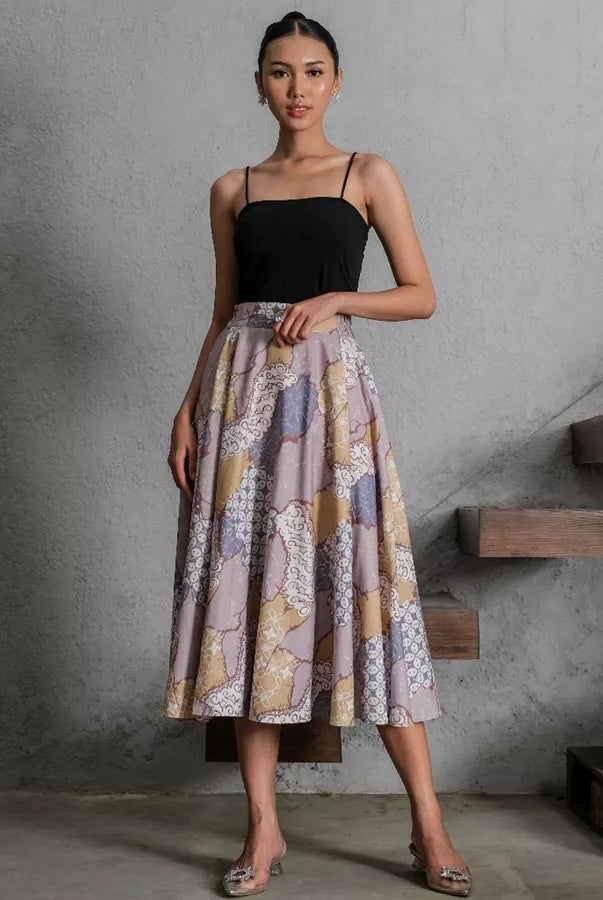 Woman wearing a black top and patterned skirt by Holy Peony standing in a modern interior setting.