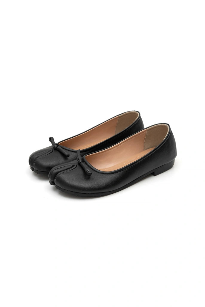 Pair of black tabi flat shoes by Cajsa with a bow on a white background