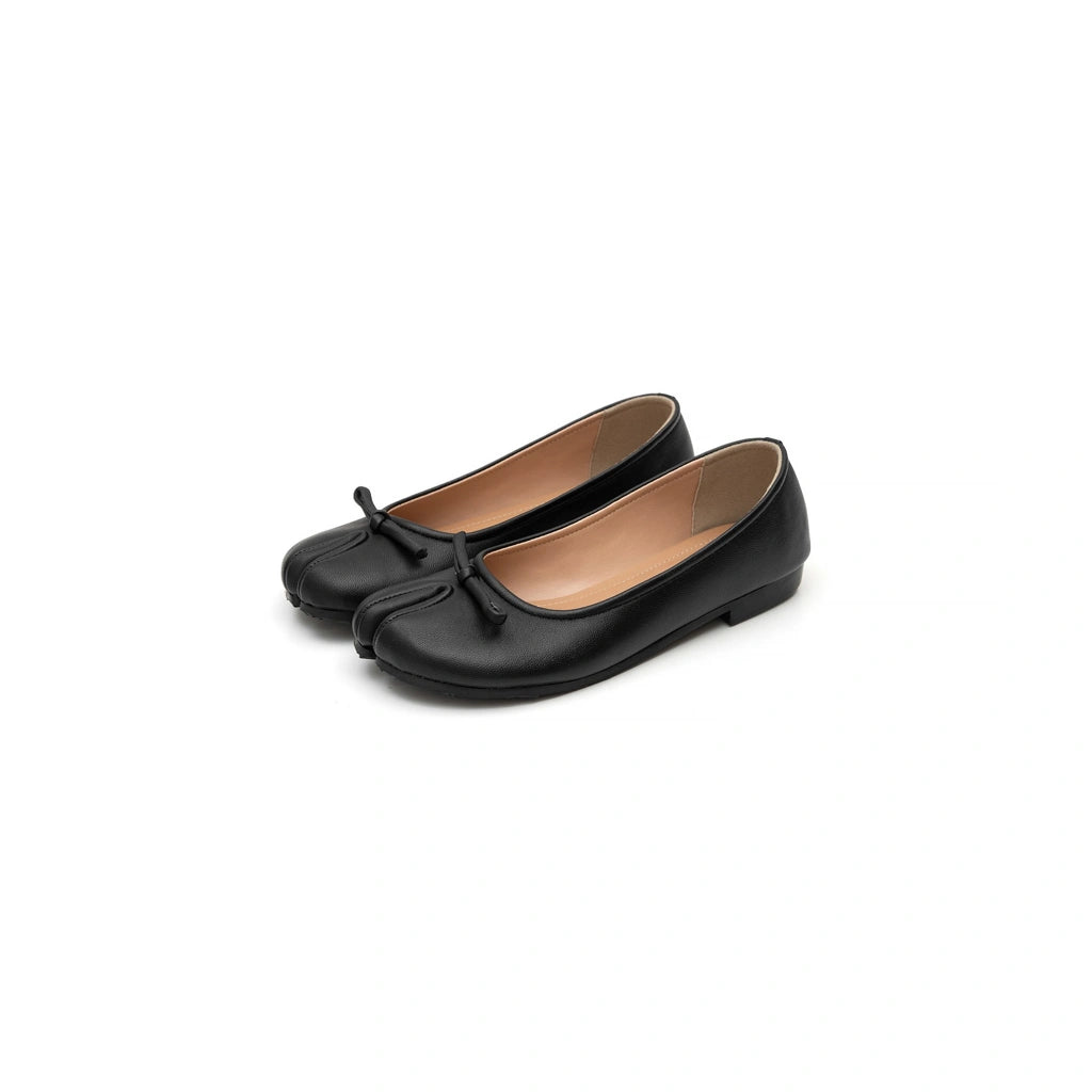Pair of black tabi flat shoes by Cajsa with a bow on a white background