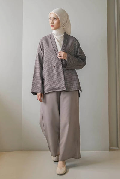 Woman wearing a latte-colored checkered blazer by Mistyvori with a hijab against a plain background