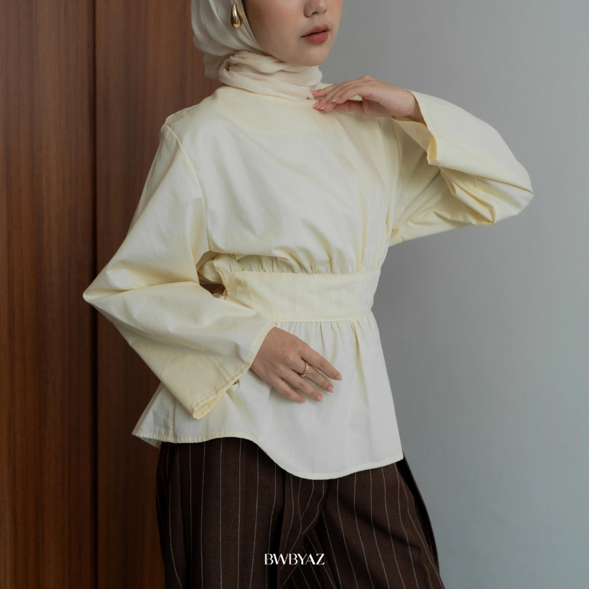 Person wearing a cream-colored blouse with wide sleeves by BWBYAZ against a neutral background