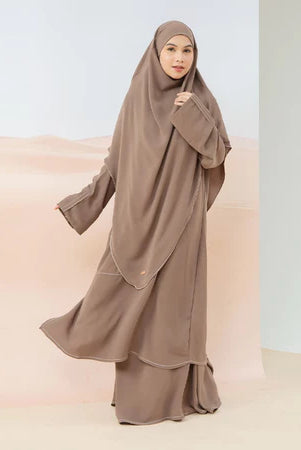 A woman wearing a brown Lozy Hijab abaya set, which includes a long dress and a matching khimar.