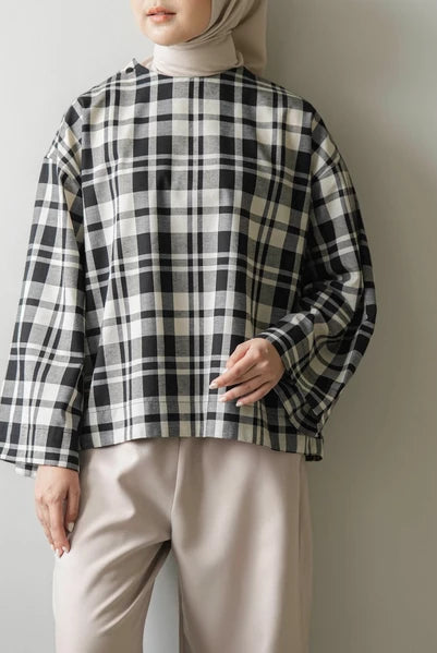 Person wearing a black and white checkered blouse by Mistyvori with beige pants against a plain background