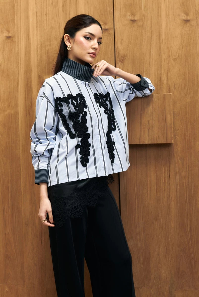 Woman wearing a black and white striped shirt with black floral patterns by Studio Tui against a wooden background