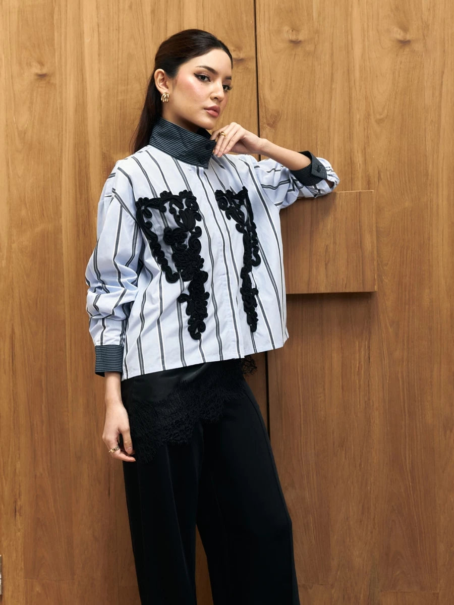 Woman wearing a black and white striped shirt with black floral patterns by Studio Tui against a wooden background