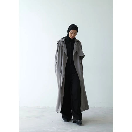 Person wearing a long gray coat over a black outfit and drawstring pants by Rashawl on a white background