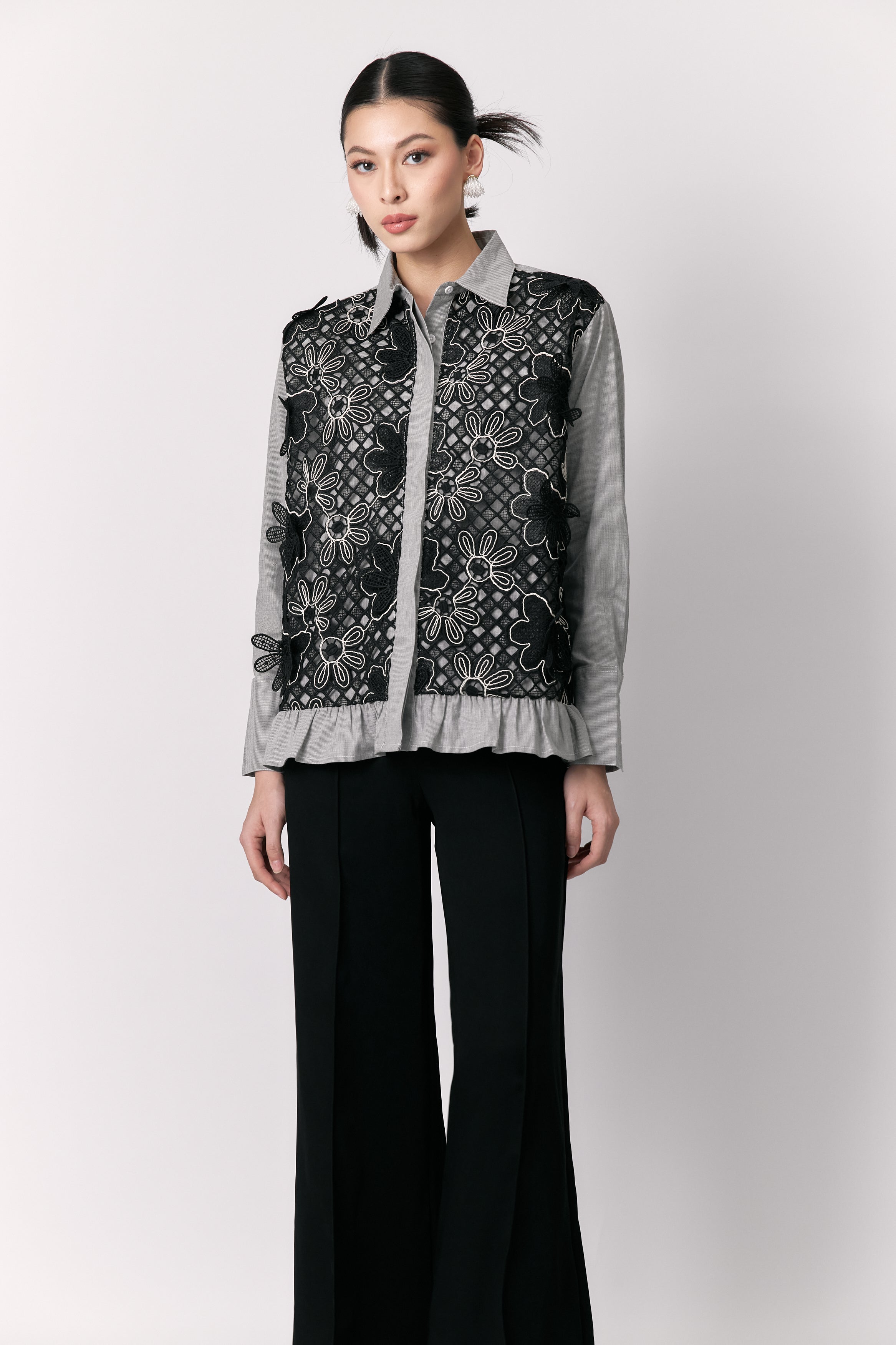 Person wearing a patterned shirt by Studio Tui with black pants on a white background