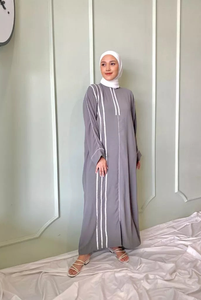 A person wearing a gray dress by Abame with white vertical stripes, standing against a neutral background.