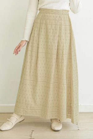 Person wearing a butter-colored patterned skirt by Mistyvori with a white top on a light wooden floor.