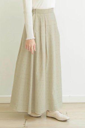 Person wearing a long khaky skirt by Mistyvori with a white top and shoes on a light wooden floor.