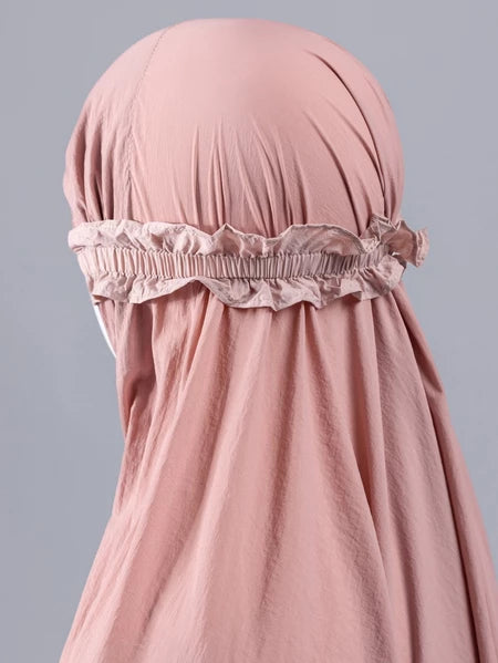 Mannequin wearing a light pink mukena for kids from Muhajir Project on a gray background