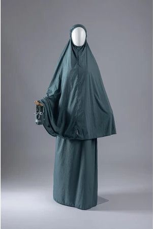 Dark green mukena from Muhajir Project on a mannequin against a gray background