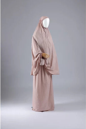 Light peach mukena from Muhajir Project on a mannequin against a gray background