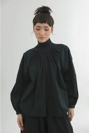 Person wearing a black blouse by Yestoday with a high collar against a white background