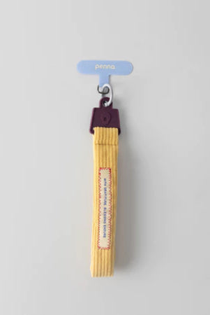 Yellow keychain strap with a dark purple handle from Muhajir Project on a gray background