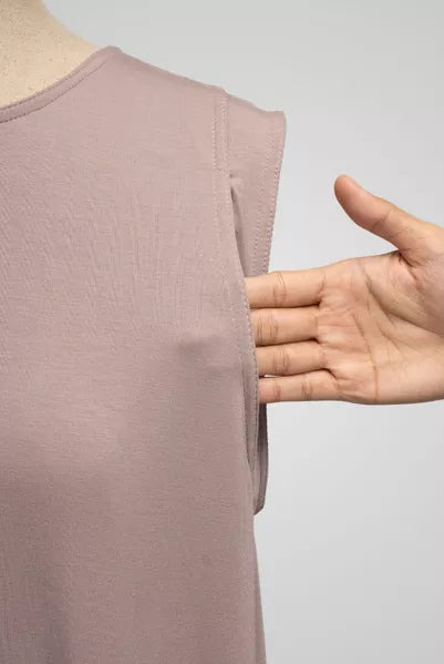 Light pink sleeveless top on a mannequin with a hand pointing to it, against a gray background
