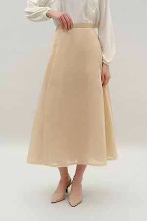 Person wearing a beige skirt by Kasa Heritage and white blouse on a plain background