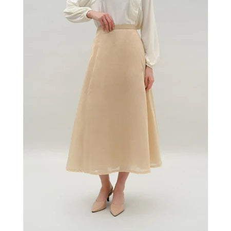 Person wearing a beige skirt by Kasa Heritage and white blouse on a plain background