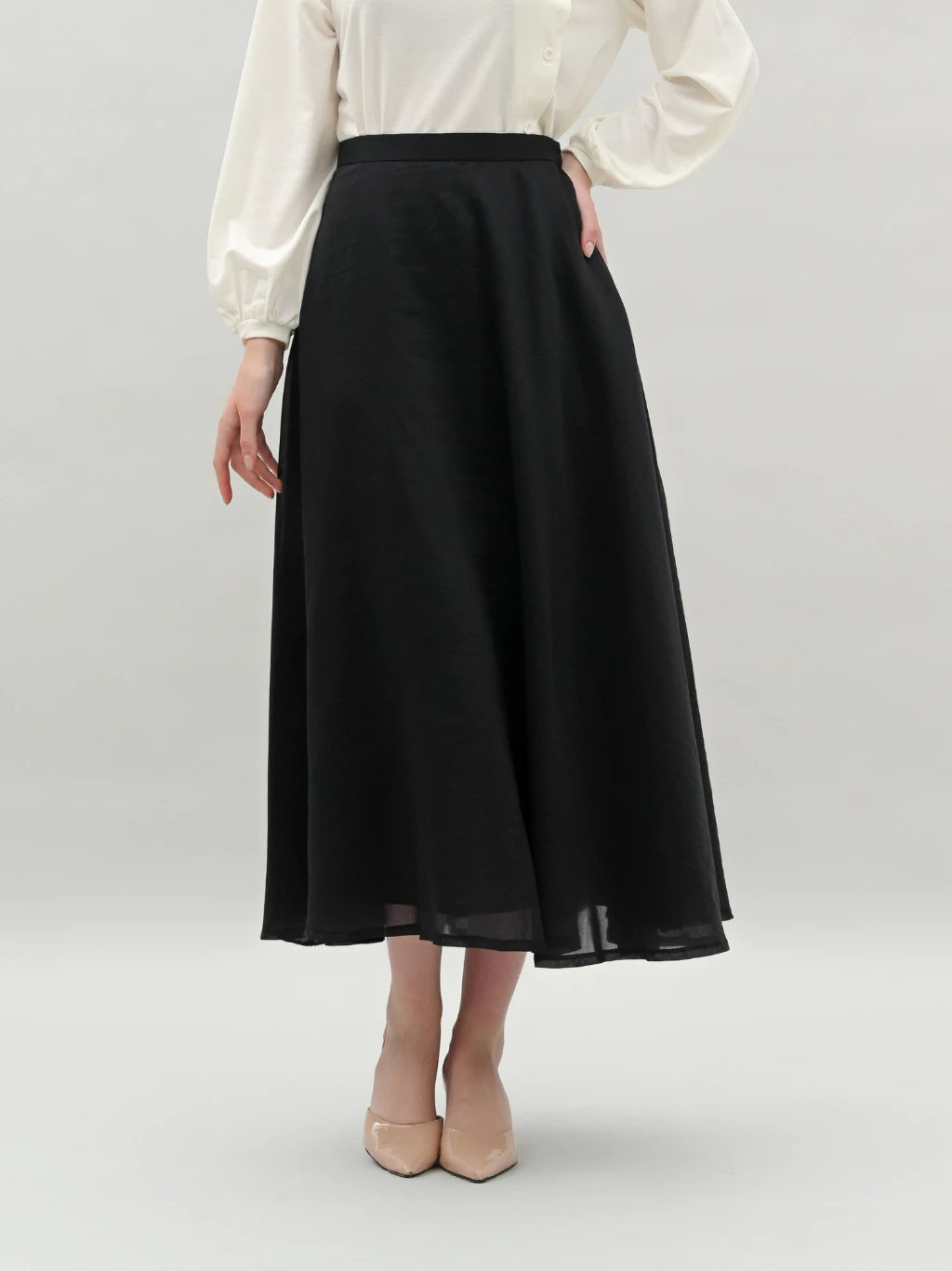 Person wearing a black skirt by Kasa Heritage and white blouse on a plain background