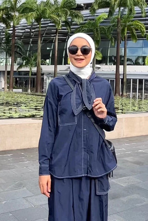 A woman standing outdoors wearing a navy shirt with long sleeves and a round neckline by Casa Elana, the shirt appears to be made of crinkle fabric.