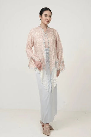 Woman wearing a traditional kebaya by Kartinis Label with light gray skirt on a white background