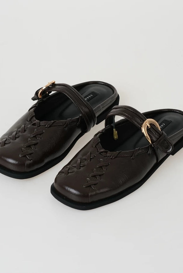 Pair of brown sandals by Cekhas with a strap on a light gray background