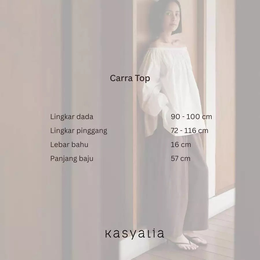 A woman wearing a white off-the-shoulder long-sleeve top and wide-leg pants stands indoors against a light wall, with text overlays showing garment measurements for 'Carra Top' and the brand name 'kasyalia'.