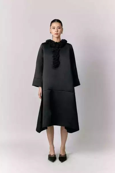 Woman wearing a black dress by Studio Tui with ruffled details on a white background