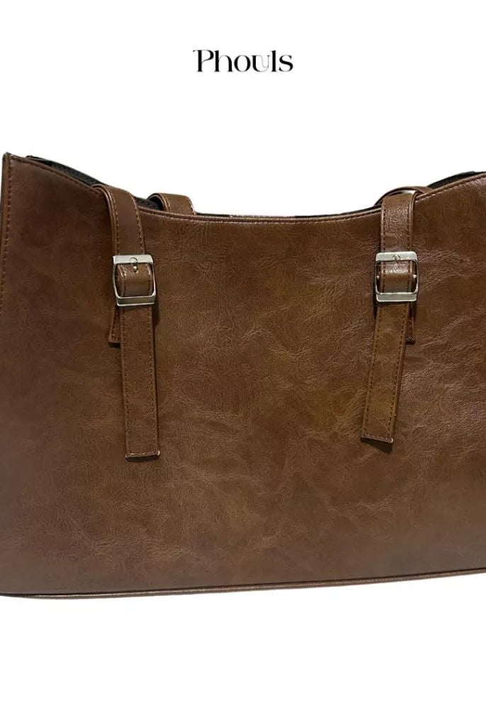 A dark brown shoulder bag with double handles and a debossed logo of Phouls.
