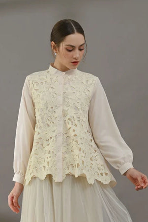 Woman wearing a light yellow blouse with lace detailing by Kasa Heritage on a gray background