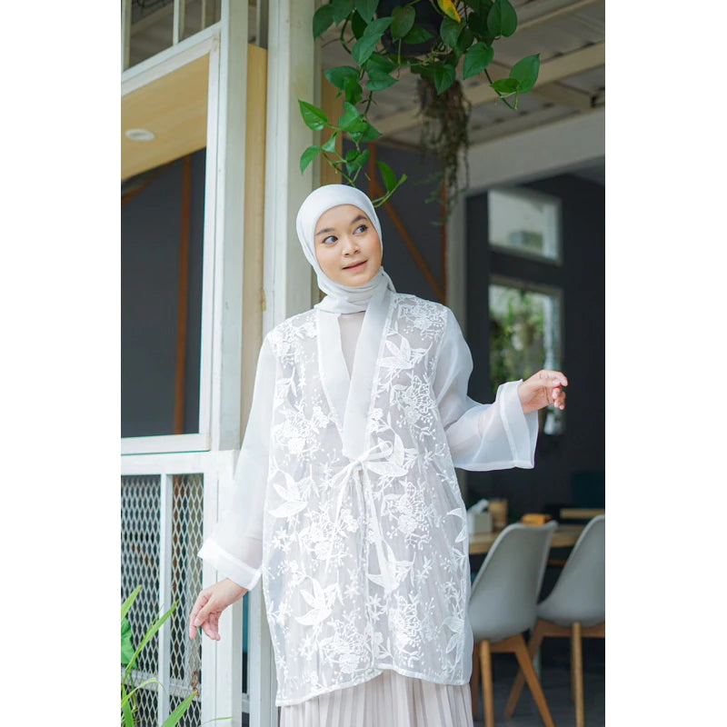 Woman wearing a white lace outer by Casa Elana standing in front of a building entrance.