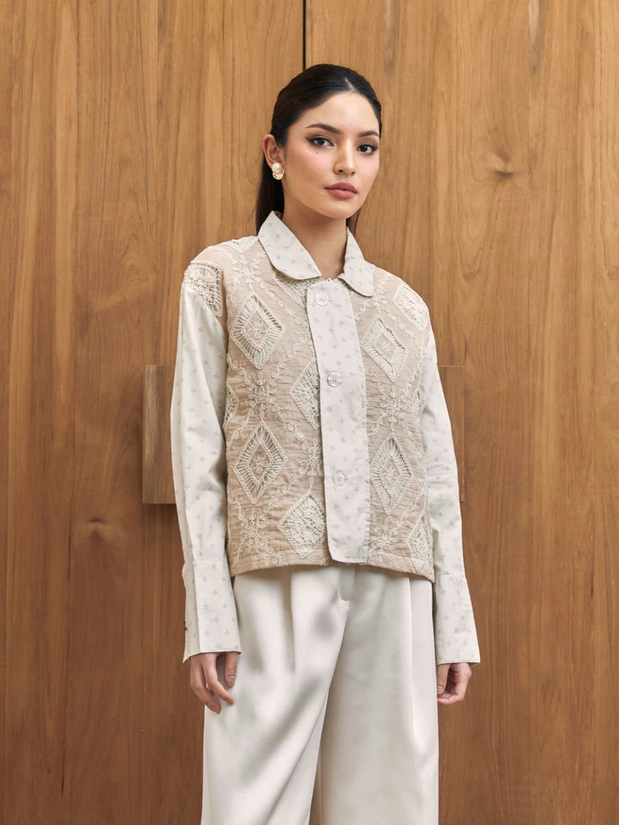 Woman wearing a textured jacket with a geometric pattern by Studio Tui against a wooden background