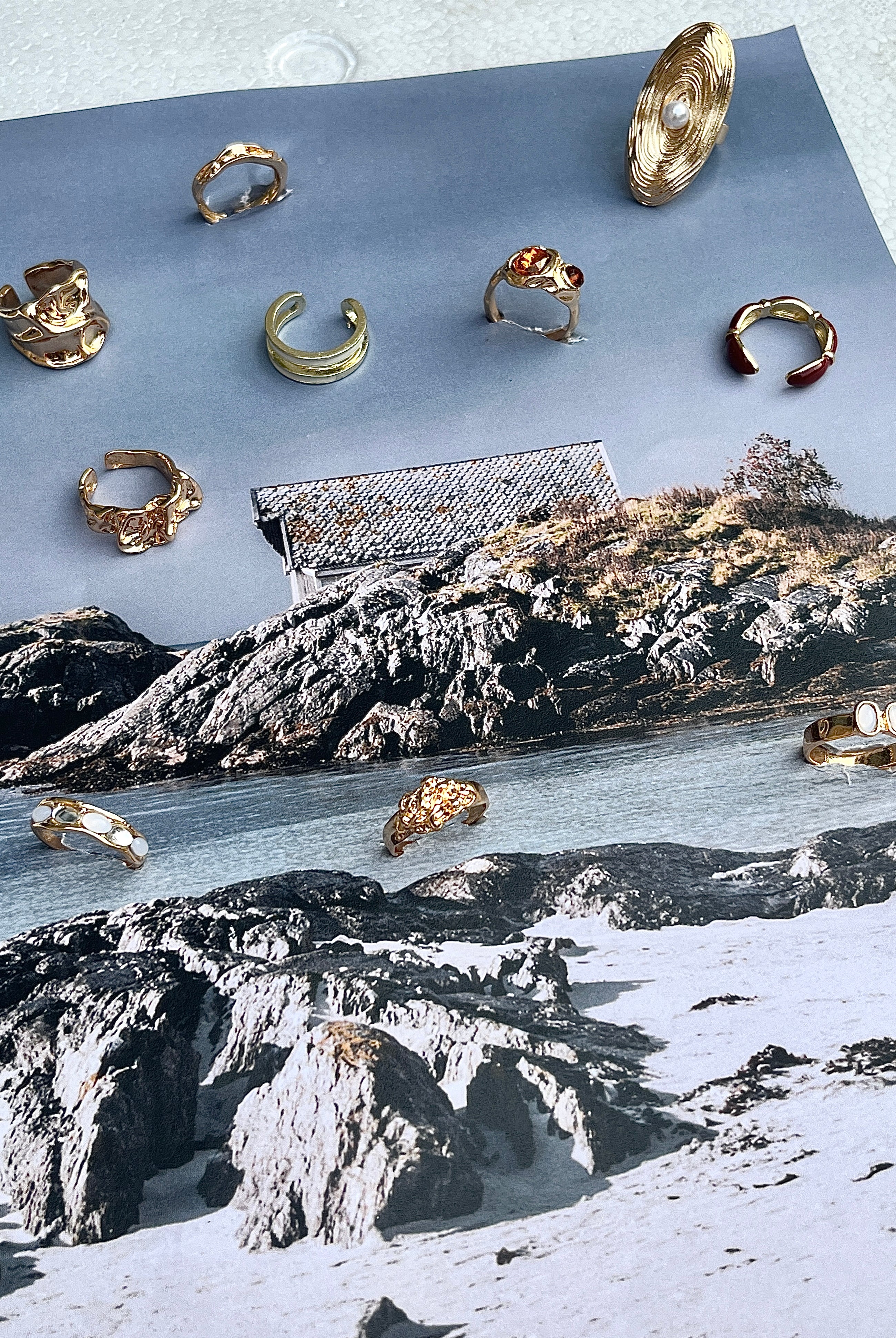 Gold rings by Darje displayed on a piece of paper with a scenic background