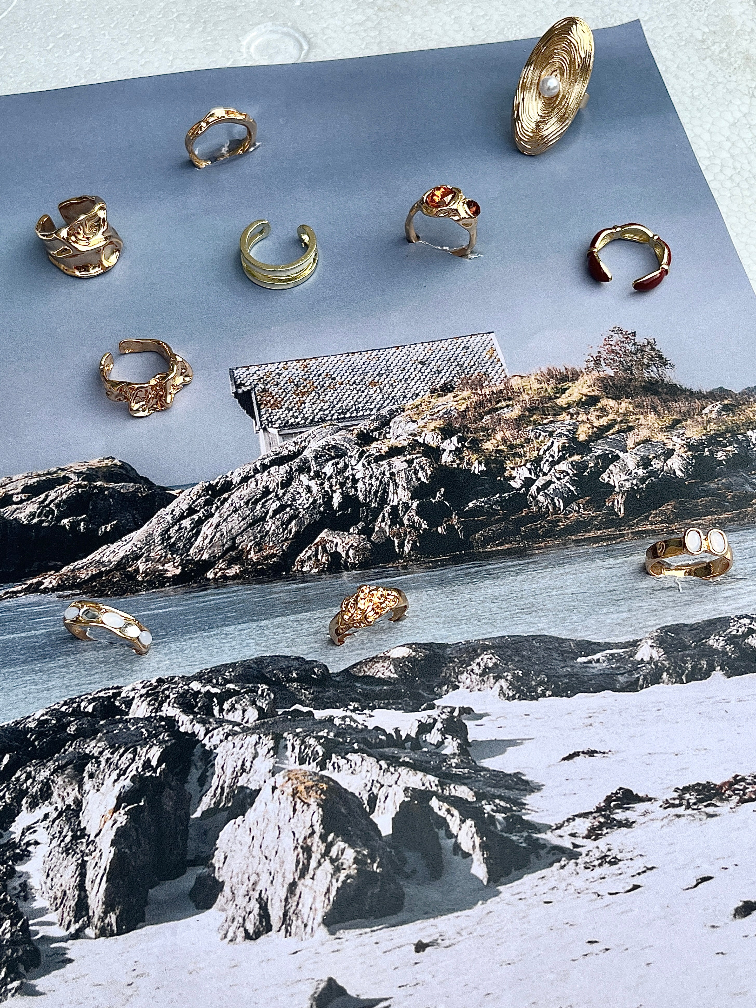 Gold rings by Darje displayed on a piece of paper with a scenic background