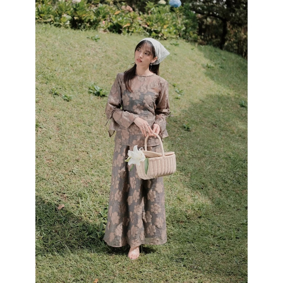 Woman in a ash brown floral outfit with floral embroidery by Renaette holding a basket in a grassy field